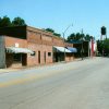 Brick storefronts on two-lane street with water tower in the background