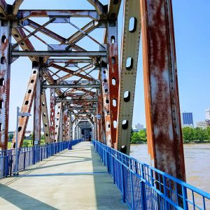 Looking down steel arch bridge with concrete platform and railings