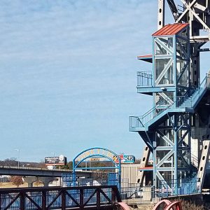 Close-up of entrance to steel arch walking bridge with elevator and stairs