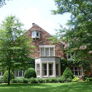 Multistory brick house behind trees in front yard