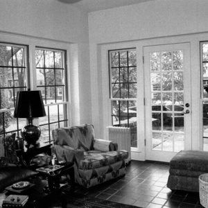 Couch and chairs with tables and lamp in room with paneled windows and door