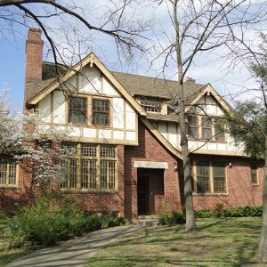 Two-story wood and brick house with trees and walking path