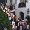 large African-American family posing with white man on staircase of multistory building with arched windows and white paint