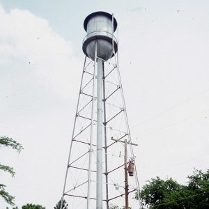 Truck and water tower inside fence on street