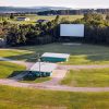 Vacant drive-in theater in sunshine with screen buildings and driveways and rolling hills in background