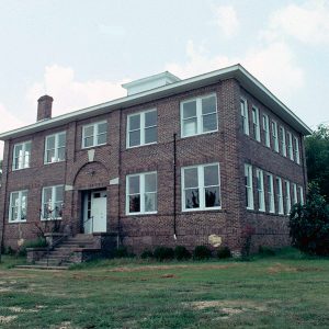 Multistory brick building with arched entrance way and rows of windows