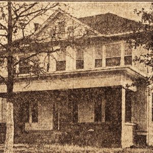 Multistory building with covered porch and tree in the foreground