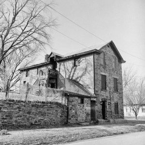 Three-story stone building with stone wall and street