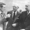 White man in suit talking to older white men with in suits