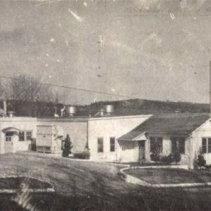 Single-story factory building with smoke stacks and covered car port