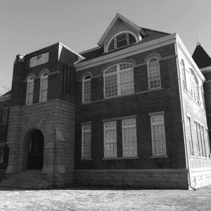 Multistory brick building with arched entrance and windows