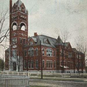 Three-story brick building with tall bell tower and spire