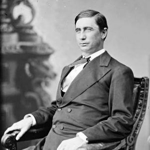 White man in suit sitting in chair