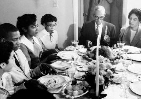 Older African American man and woman at dinner table with younger African American boys and girls