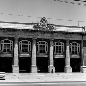 Multistory ornate fire department building with four columns and five garage bays