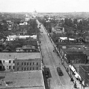 View of city street and buildings leading up to state capitol building in background from above