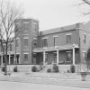 multistory brick building with central tower and grounds