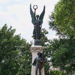 Tall stone monument with statue of soldier and angel on top