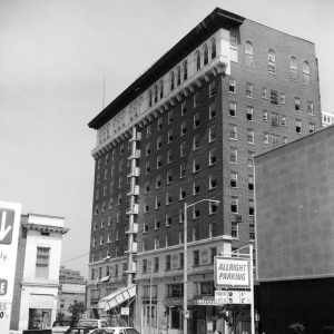 Multistory hotel building on city street with cars in parking lot