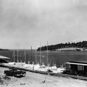 Car driving passed boat dock with boats on a lake