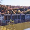 Concrete dam on river with tree covered mountain in the background