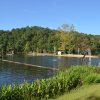 roped off swimming area with slide on lake with trees in the background