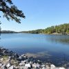 Lake with rocks in the foreground and trees on shore in the background