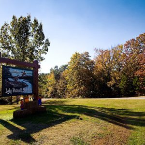 "Lake Poinsett State Park" sign on grass with hay bales with dolls