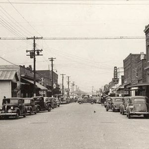 Parked cars outside rows of multistory buildings on town street