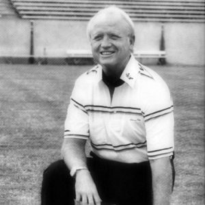 Older white man kneeling on football field