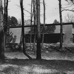 Side view of two-story brick building with trees in the foreground