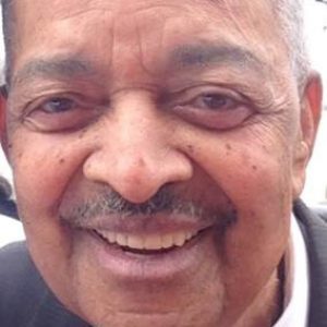 Older African-American man with mustache smiling in suit