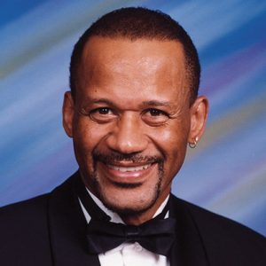 African-American man with mustache smiling in tuxedo