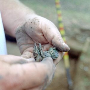 White person's hands holding the remains of a leather pouch