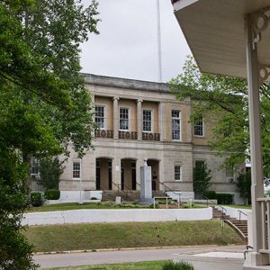 Two-story stone building with three-arch entrance and gazebo