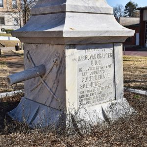 Crossed swords and cannon and raised relief wording on base of stone monument