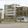 Multistory industrial buildings and silos with outbuilding and railroad tracks in the foreground