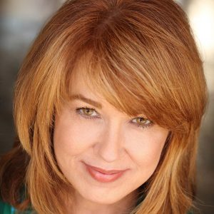 White woman with red hair smiling in green shirt