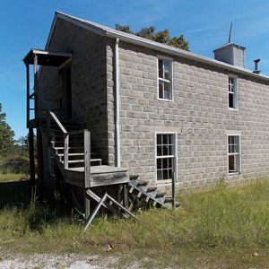 Multistory gray brick building with wooden staircase at side entrance