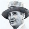 White man with straw hat in suit and tie wearing a carnation corsage