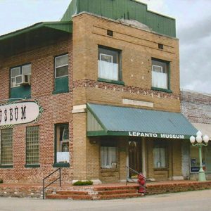 Two-story brick storefront with "Museum" written on the side with green roof and awning over front entrance