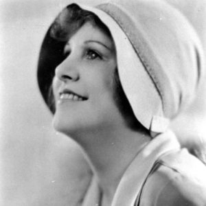 White woman in hat and fur coat with face tilted up and smiling