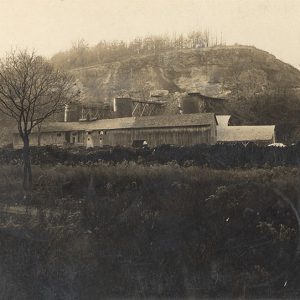 Wooden buildings in front of stone cliff face