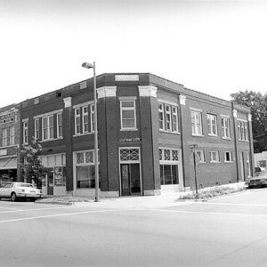 Two-story brick building on street corner with parked cars