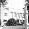 Three-story brick building with stone monuments and trees