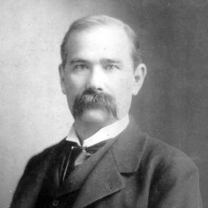 White man with mustache in suit and tie