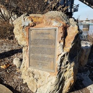 Large rock with weathered plaque on it near river