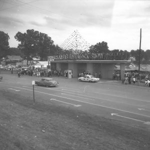 crowd at entrance gate on multilane street with houses in the background