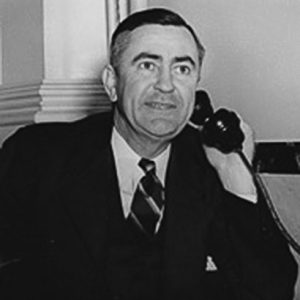 White man in suit and tie using a telephone