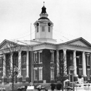 Two-story building with central clock tower and identical columned entrances